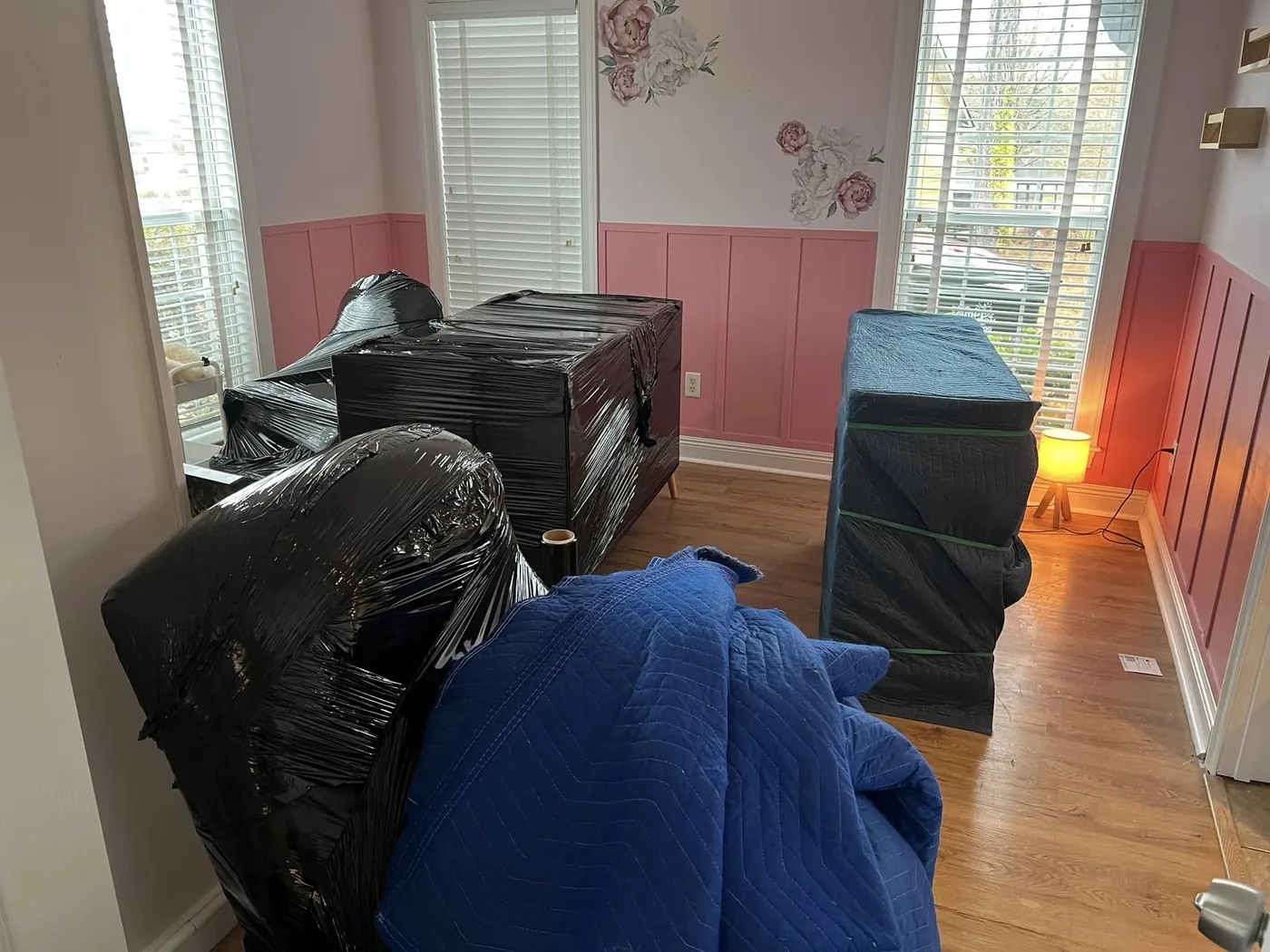 Perez Moving Co crew lifting a large blanket-wrapped piece of furniture