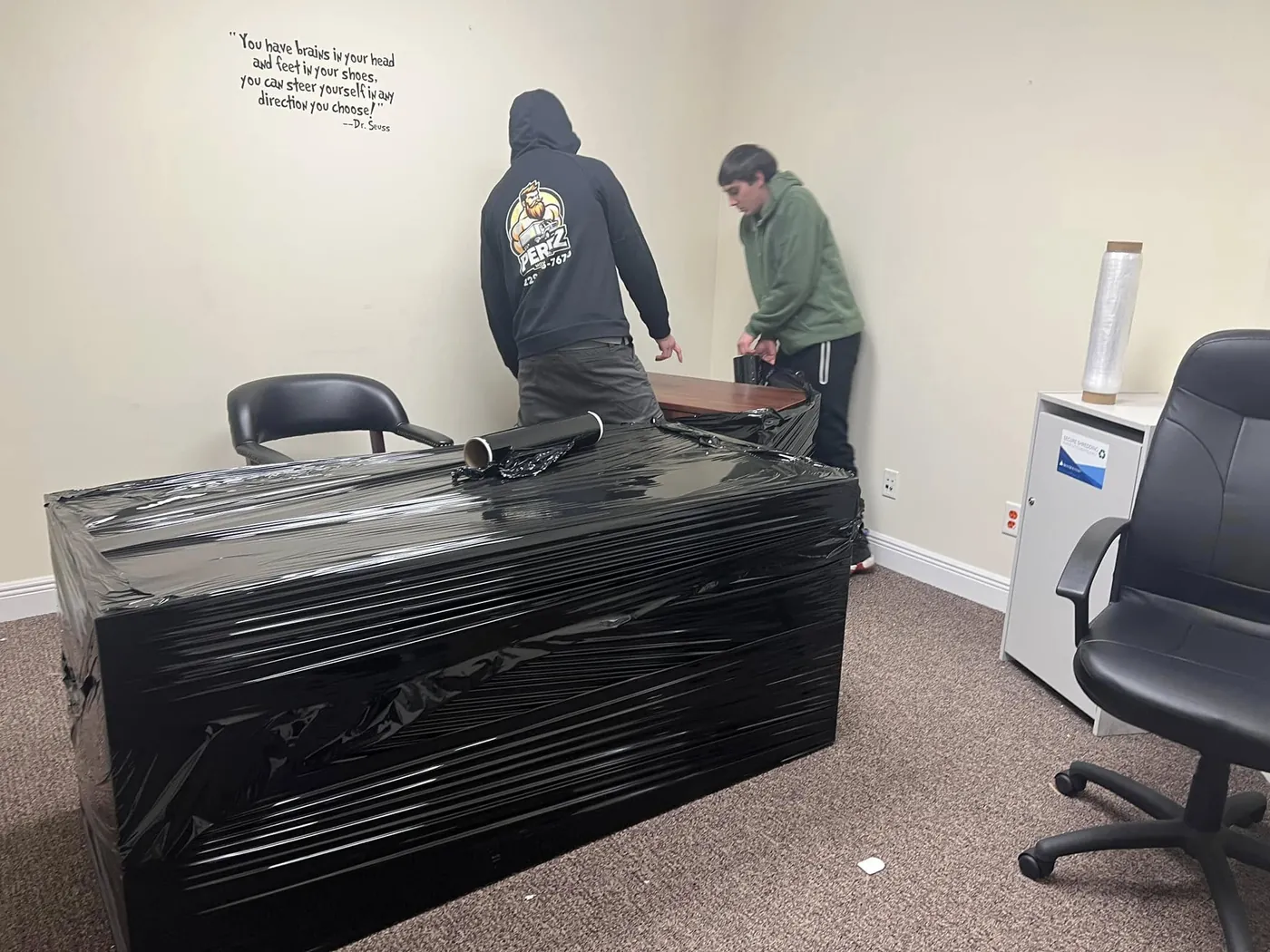 Perez Moving Co movers shrink-wrapping an office desk for a commercial move